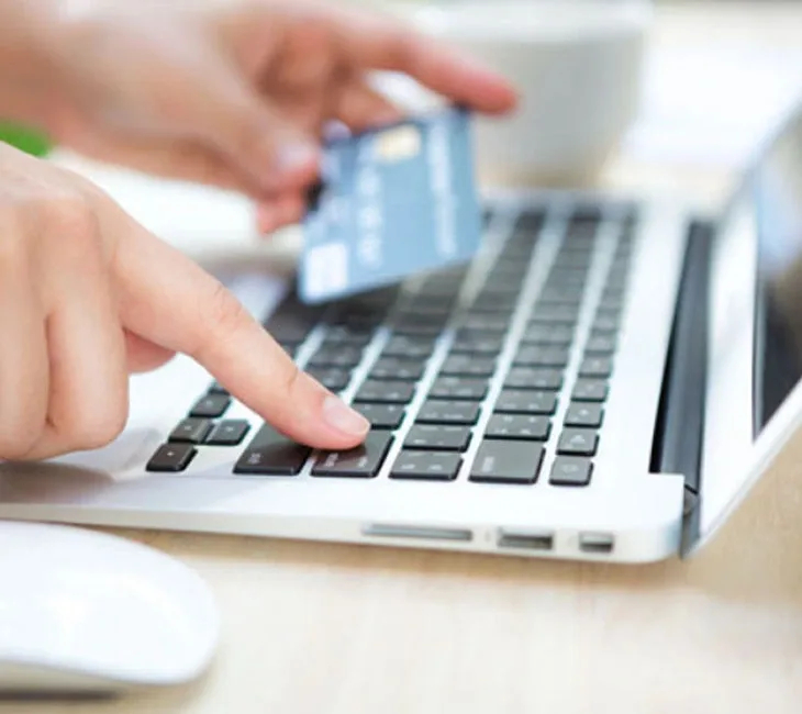Person entering information on a laptop keyboard while holding a credit card, illustrating online loan application process for California Online Loans.
