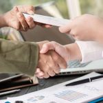 Hands shaking over a document exchange, symbolizing secure transactions and personal loan agreements in California.