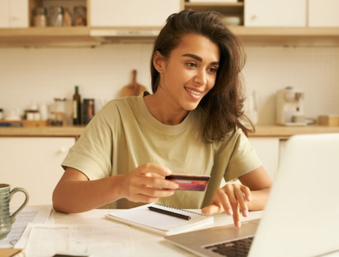 Woman using a credit card to apply for online payday loans on a laptop in a home setting, showcasing convenience and accessibility for California Online Loans.