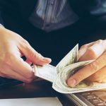 Person counting cash with a focus on financial transactions, relevant to payday loans and personal finance management.