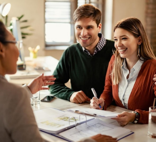 Couple discussing personal loans with a financial advisor, reviewing documents at a table in a professional setting.